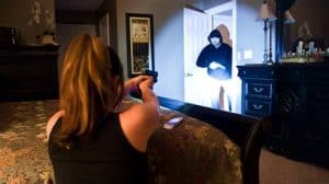 Picture of woman holding a firearm as someone enters her home.
