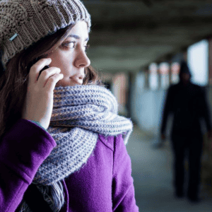 individual in the shadows following woman in dim hallway.